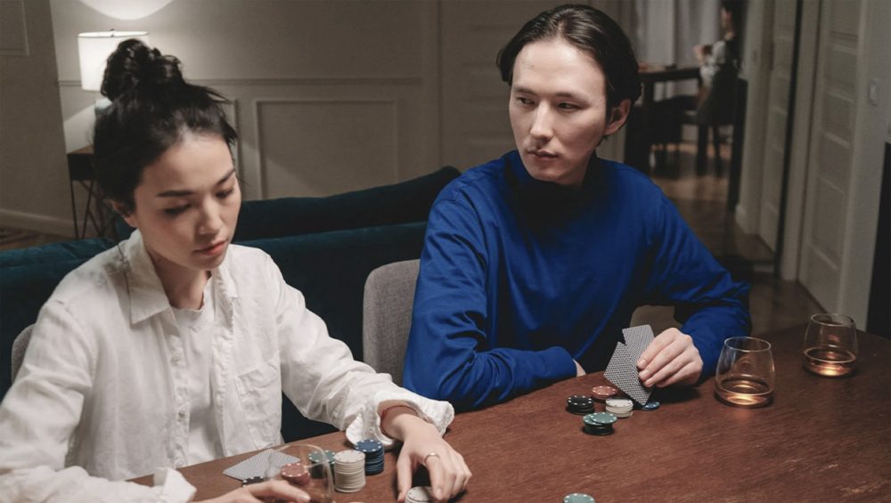 man-watching-girl-reach-for-betting-chips-poker-game