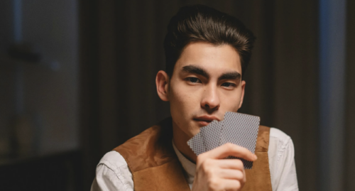 a mysterious man holding poker cards in front of his face